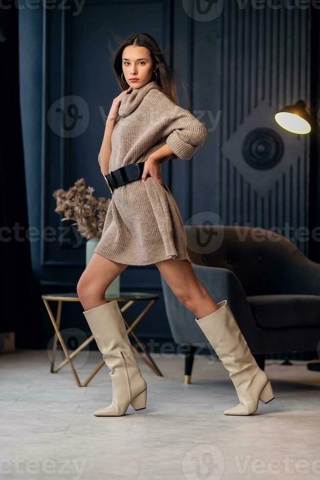 Young beautiful brunette woman in beige boots in a beautiful interior photo