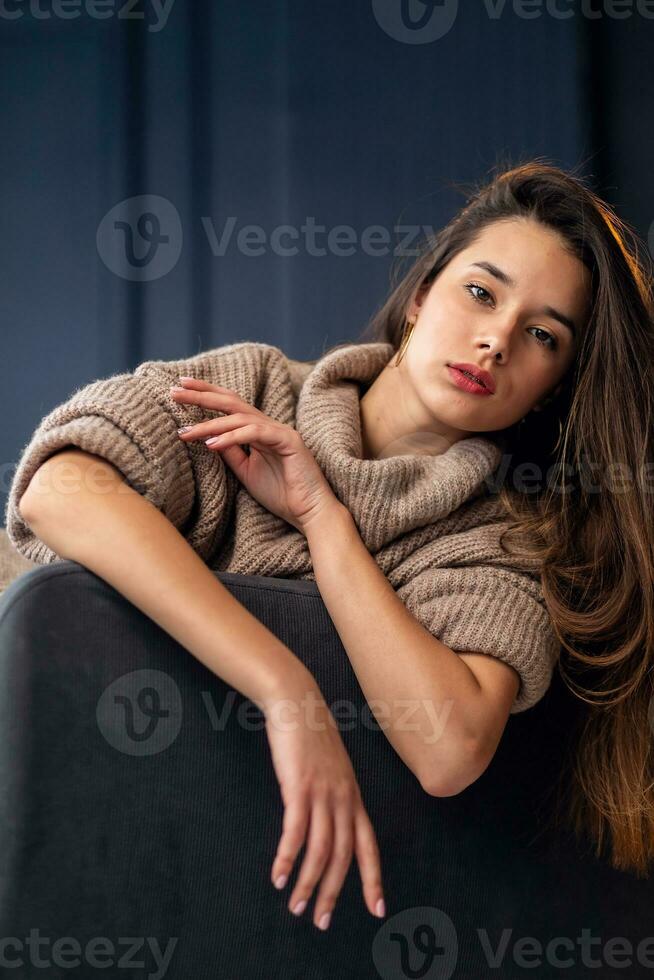 A beautiful young girl is sitting on the back of a chair. photo