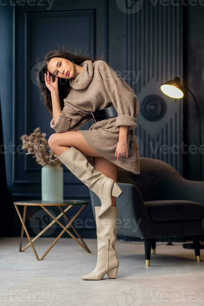 Young beautiful brunette woman in beige boots in a beautiful interior photo