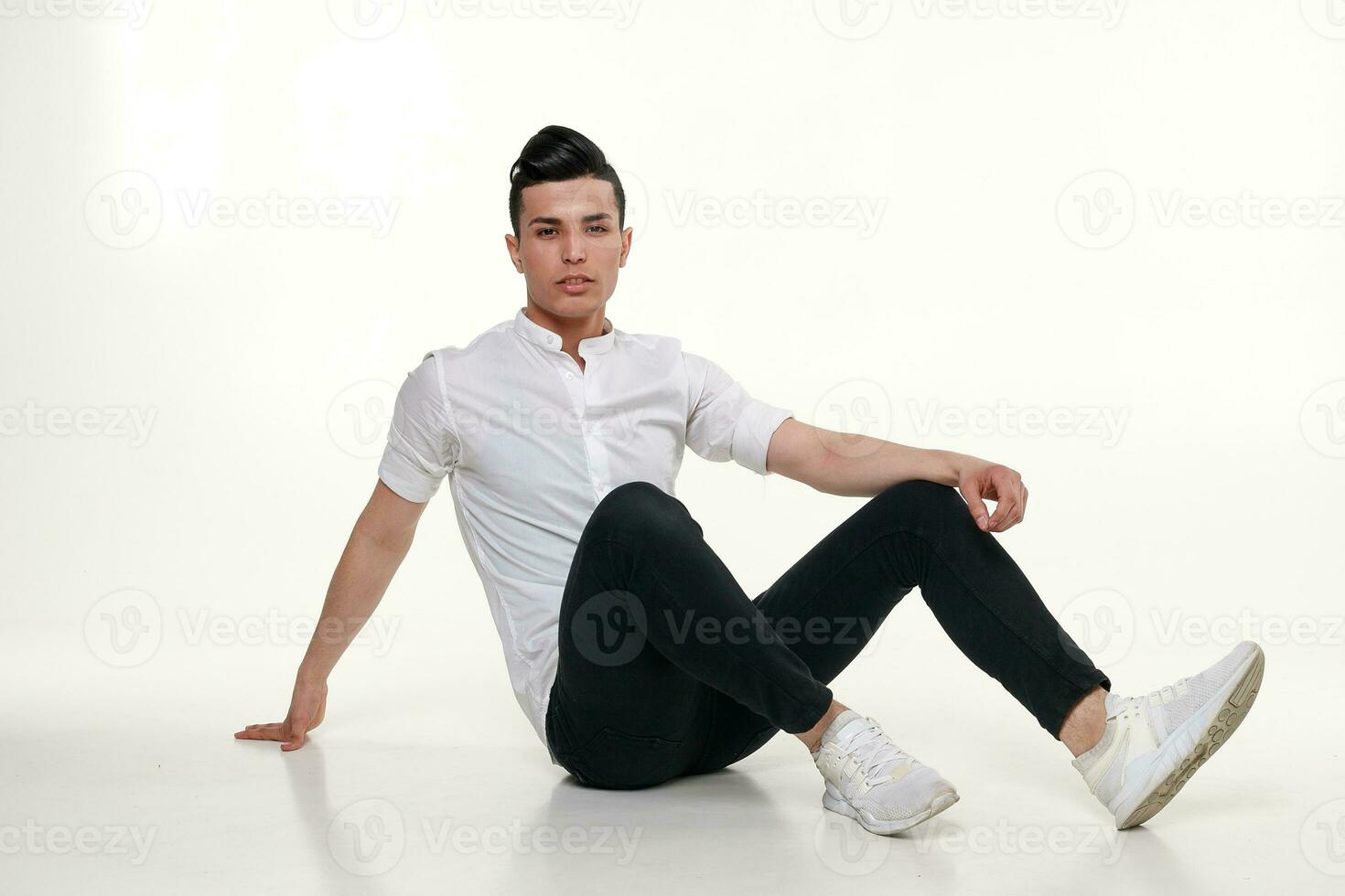 elegante, joven, de moda hombre es sentado en el piso en estudio foto