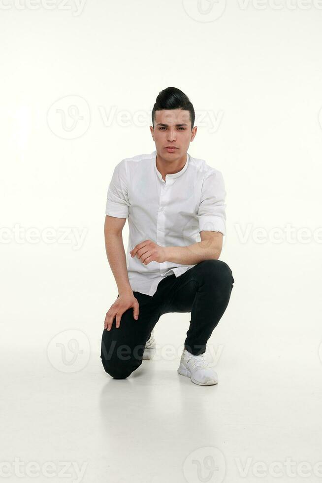 Handsome, young, trendy man is sitting on the floor in studio photo