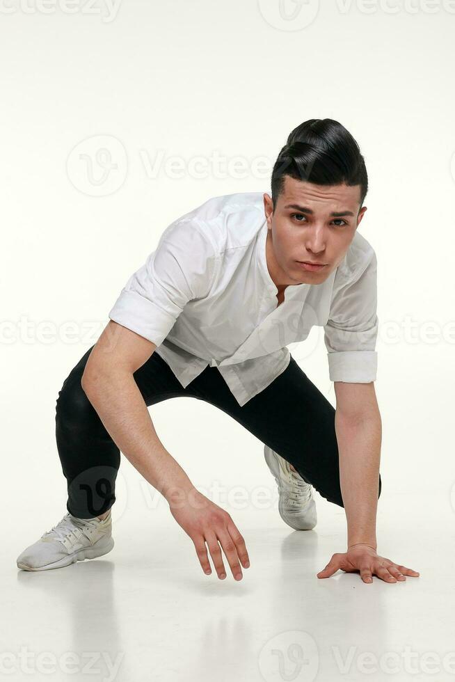 elegante, joven, de moda hombre es sentado en el piso en estudio foto