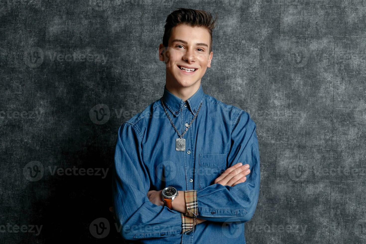 Man in denim shirt, arms on hips, gray background. photo