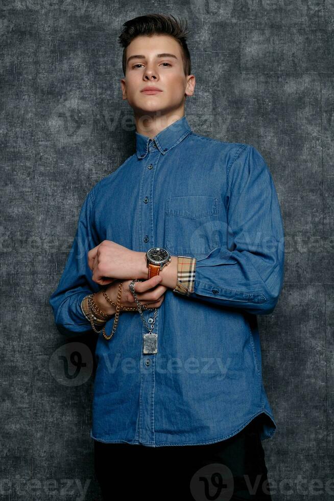 Man in denim shirt, arms on hips, gray background. photo