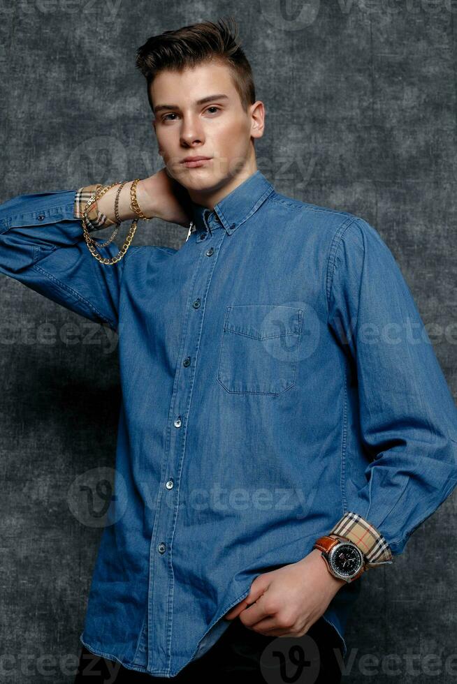 Man in denim shirt, arms on hips, gray background. photo