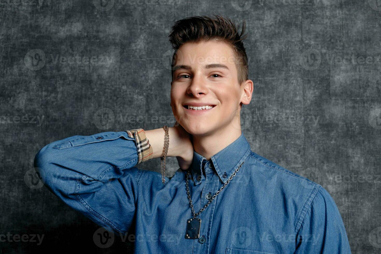 Man in denim shirt, arms on hips, gray background. photo