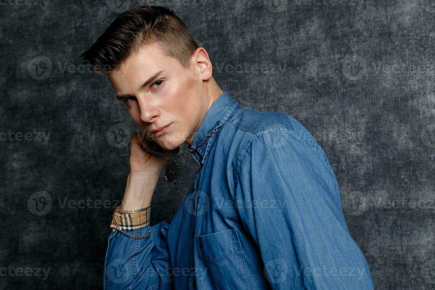 Man in denim shirt, arms on hips, gray background. photo