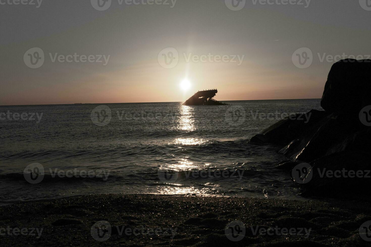 Sunset beach in Cape May New Jersey where you can get a great view of the sun going down across the ocean and the bay. The reflection of the sun on the water with the sunken ship looks so beautiful. photo