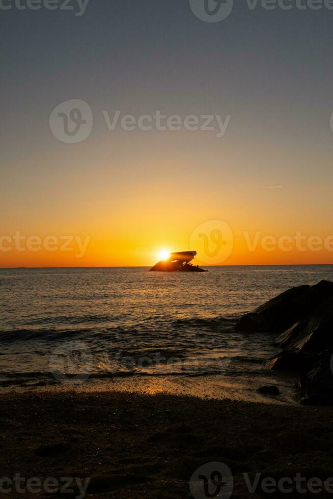 Sunset beach in Cape May New Jersey where you can get a great view of the sun going down across the ocean and the bay. The reflection of the sun on the water with the sunken ship looks so beautiful. photo