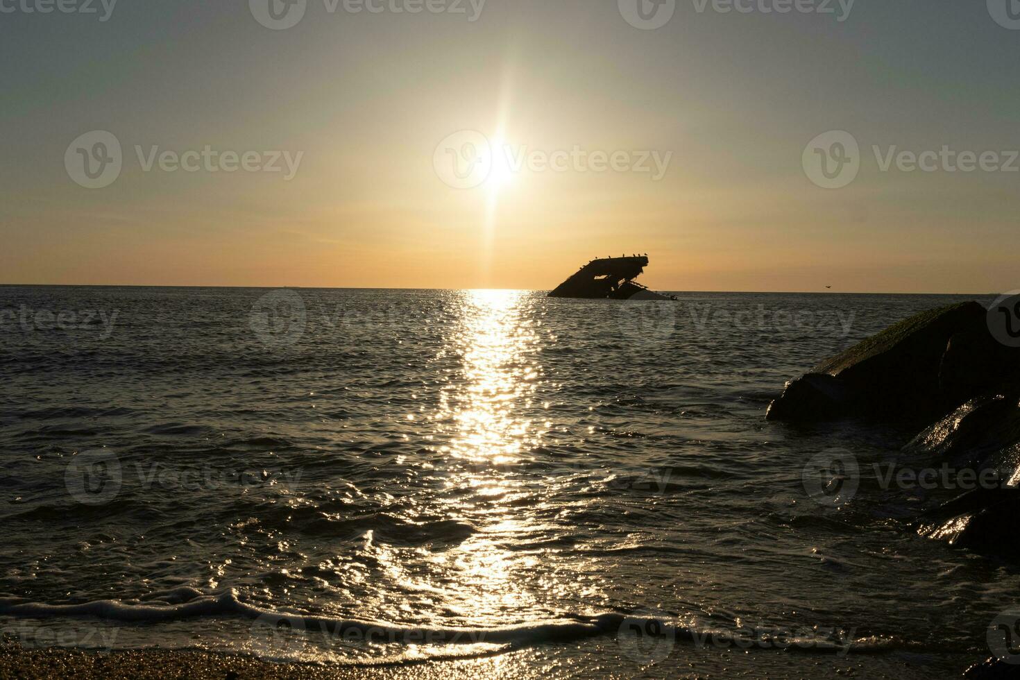 Sunset beach in Cape May New Jersey where you can get a great view of the sun going down across the ocean and the bay. The reflection of the sun on the water with the sunken ship looks so beautiful. photo