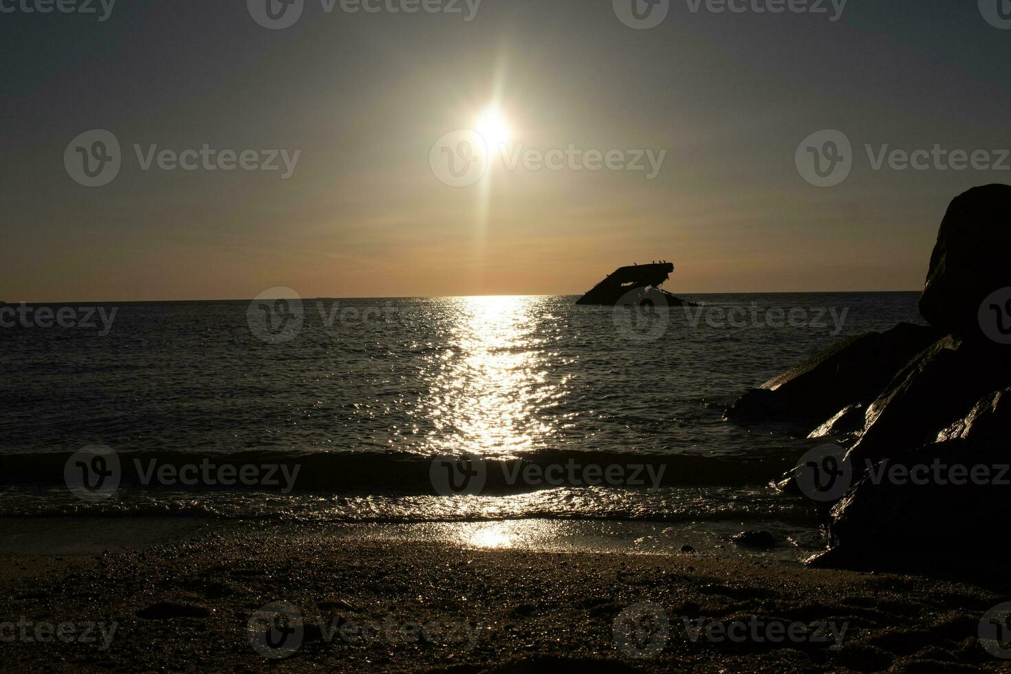Sunset beach in Cape May New Jersey where you can get a great view of the sun going down across the ocean and the bay. The reflection of the sun on the water with the sunken ship looks so beautiful. photo