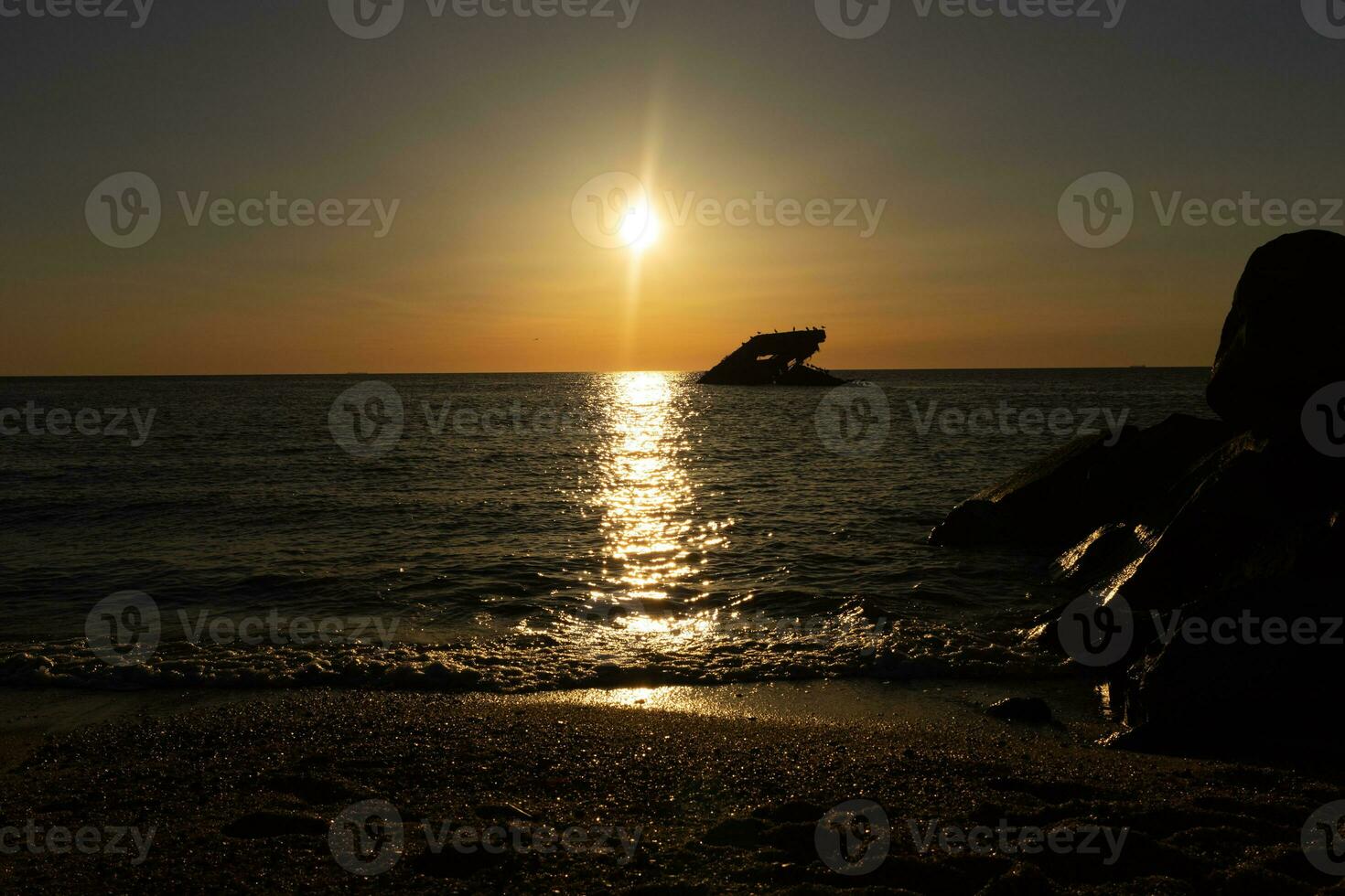 Sunset beach in Cape May New Jersey where you can get a great view of the sun going down across the ocean and the bay. The reflection of the sun on the water with the sunken ship looks so beautiful. photo