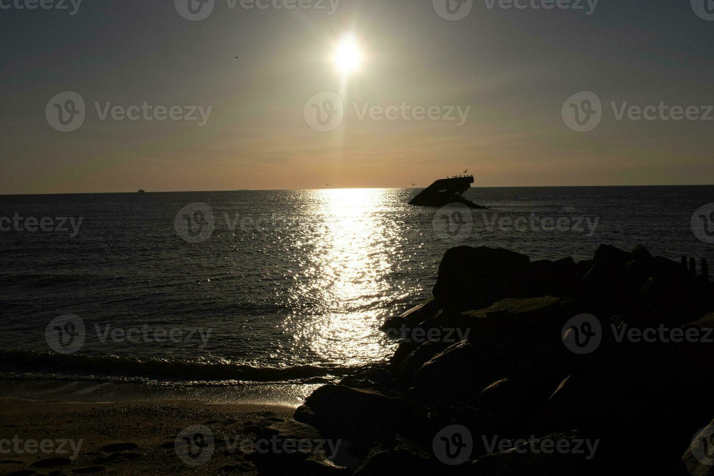 Sunset beach in Cape May New Jersey where you can get a great view of the sun going down across the ocean and the bay. The reflection of the sun on the water with the sunken ship looks so beautiful. photo