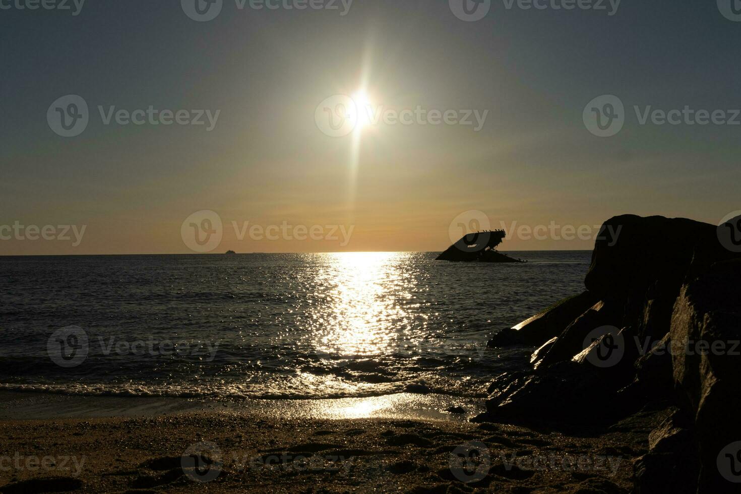 Sunset beach in Cape May New Jersey where you can get a great view of the sun going down across the ocean and the bay. The reflection of the sun on the water with the sunken ship looks so beautiful. photo