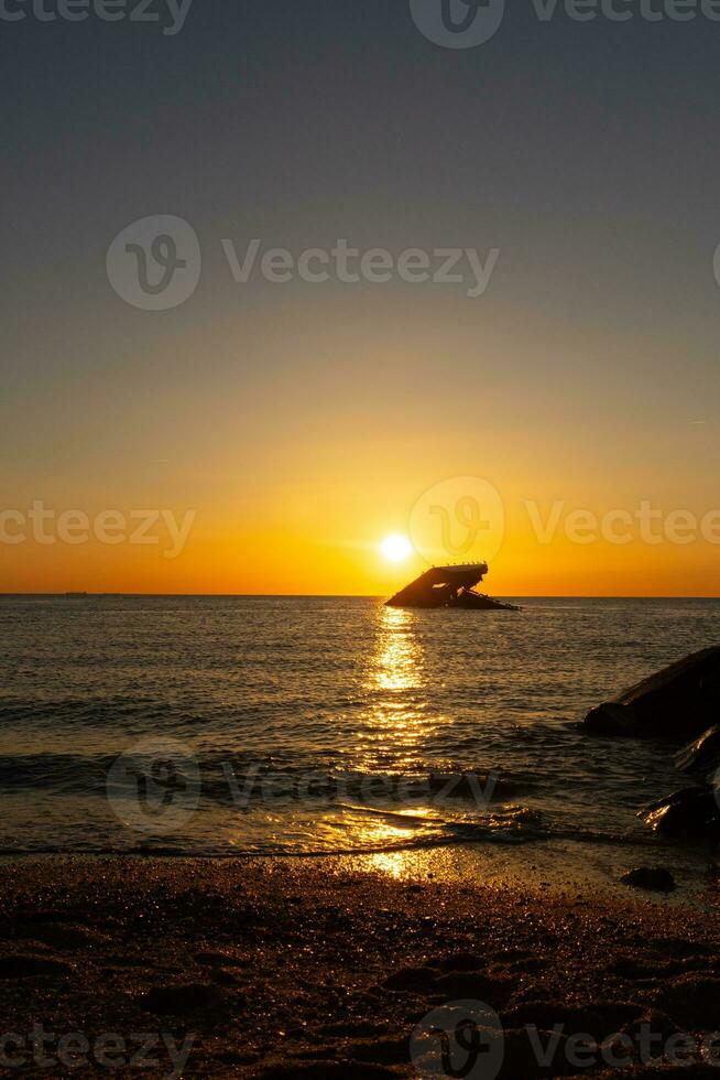 Sunset beach in Cape May New Jersey where you can get a great view of the sun going down across the ocean and the bay. The reflection of the sun on the water with the sunken ship looks so beautiful. photo