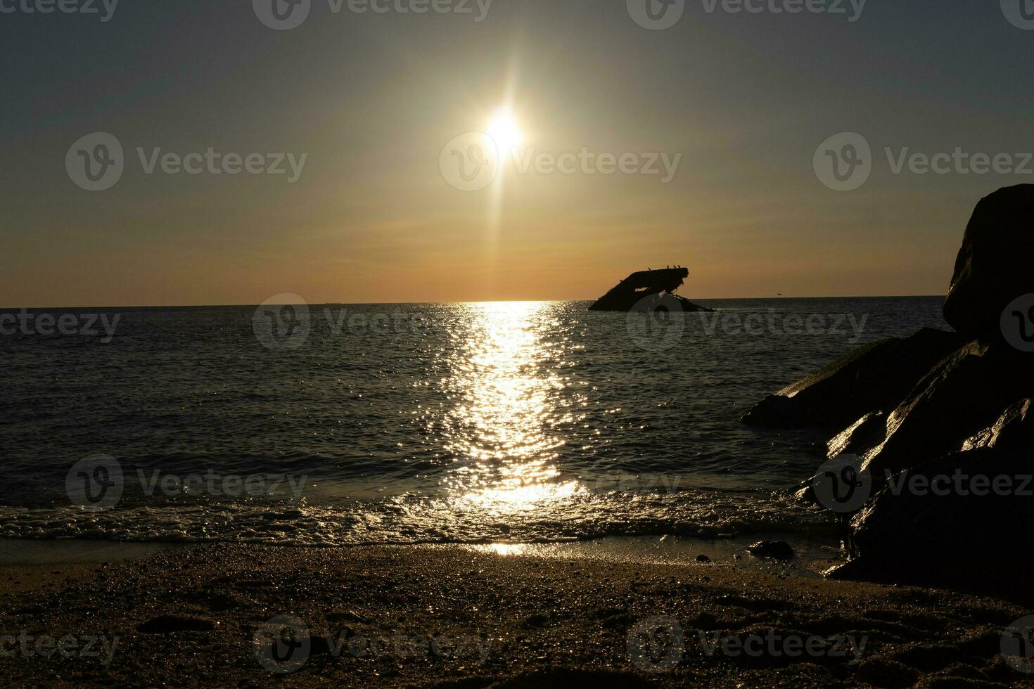 Sunset beach in Cape May New Jersey where you can get a great view of the sun going down across the ocean and the bay. The reflection of the sun on the water with the sunken ship looks so beautiful. photo