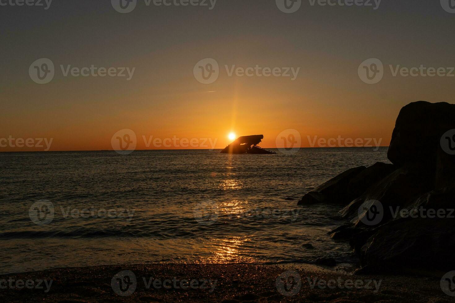 Sunset beach in Cape May New Jersey where you can get a great view of the sun going down across the ocean and the bay. The reflection of the sun on the water with the sunken ship looks so beautiful. photo