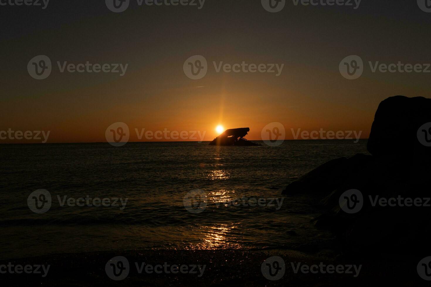 Sunset beach in Cape May New Jersey where you can get a great view of the sun going down across the ocean and the bay. The reflection of the sun on the water with the sunken ship looks so beautiful. photo
