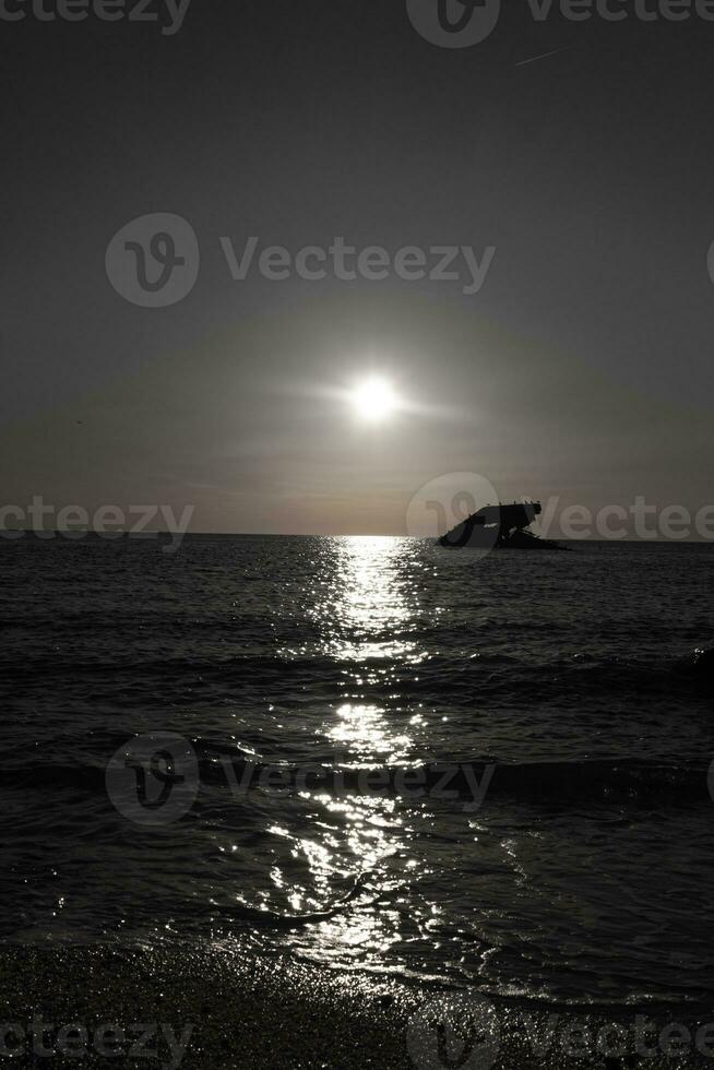 Sunset beach in Cape May New Jersey where you can get a great view of the sun going down across the ocean and the bay. The reflection of the sun on the water with the sunken ship looks so beautiful. photo