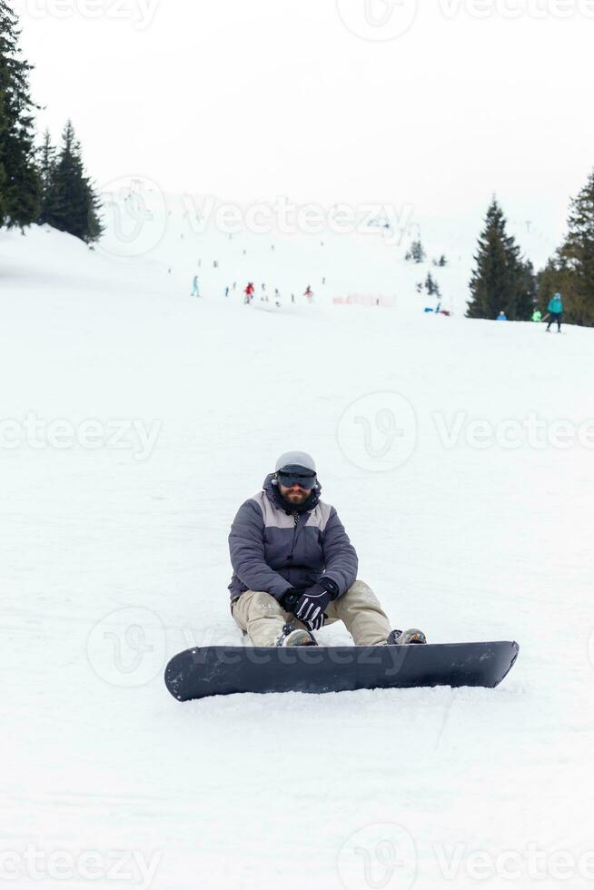 Snowboarder sitting at the top of a mountain photo