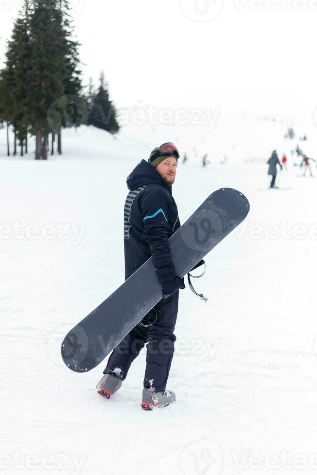 Snowboarder in helmet standing at the very top of a mountain photo