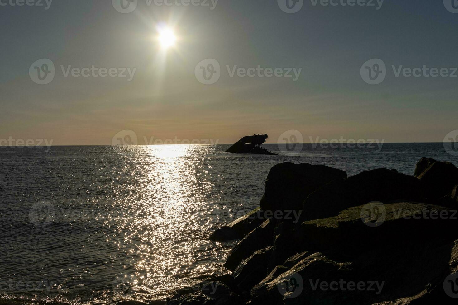 Sunset beach in Cape May New Jersey where you can get a great view of the sun going down across the ocean and the bay. The reflection of the sun on the water with the sunken ship looks so beautiful. photo