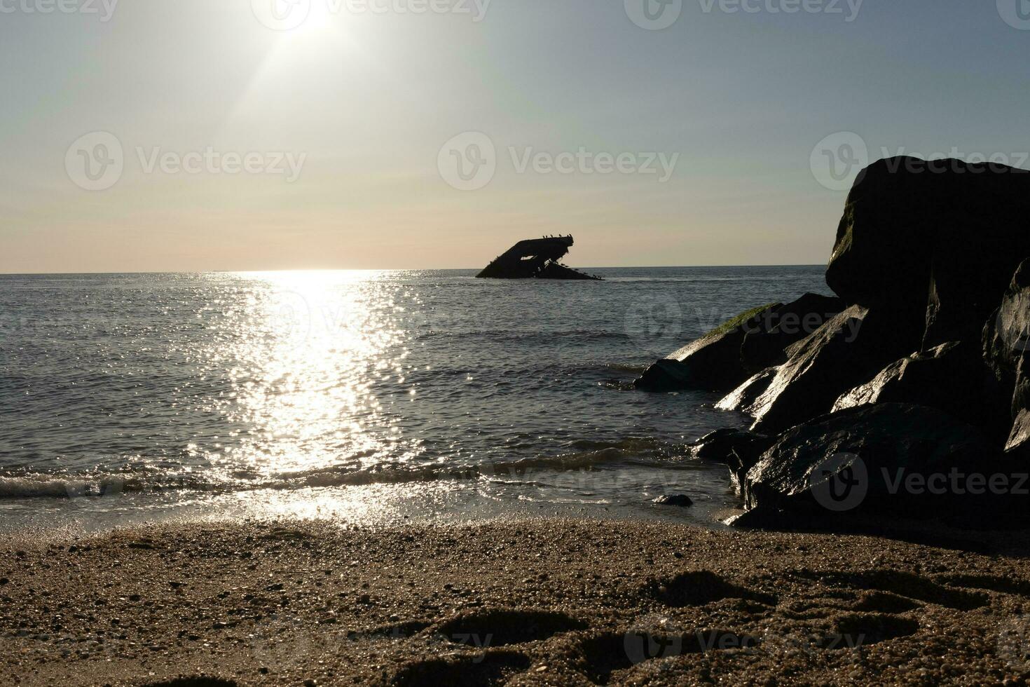 Sunset beach in Cape May New Jersey where you can get a great view of the sun going down across the ocean and the bay. The reflection of the sun on the water with the sunken ship looks so beautiful. photo