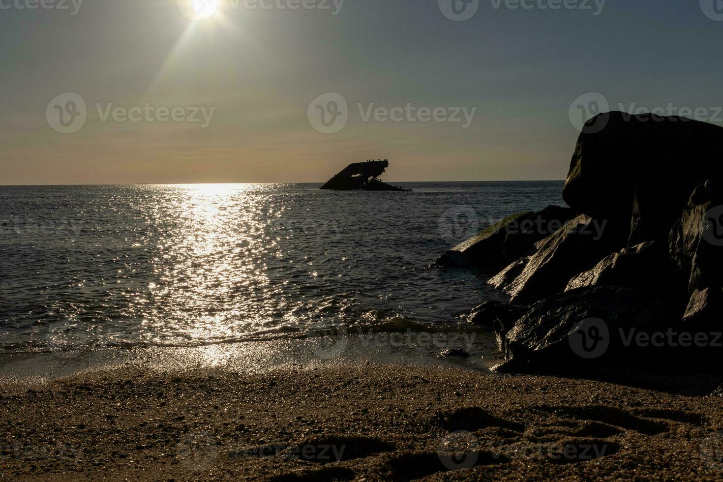 Sunset beach in Cape May New Jersey where you can get a great view of the sun going down across the ocean and the bay. The reflection of the sun on the water with the sunken ship looks so beautiful. photo