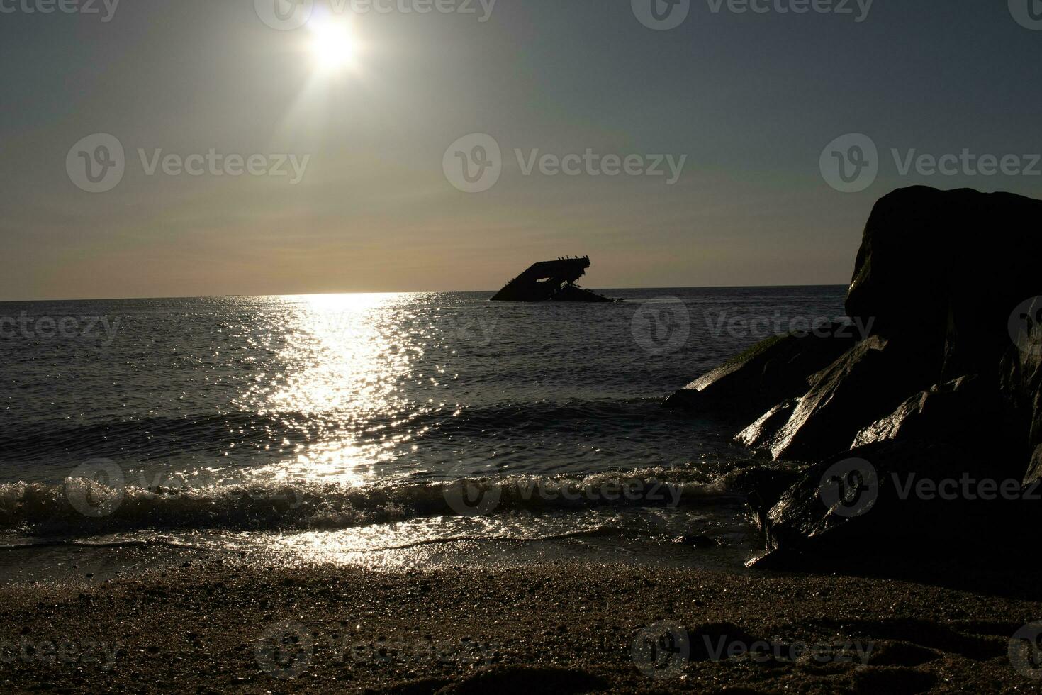 Sunset beach in Cape May New Jersey where you can get a great view of the sun going down across the ocean and the bay. The reflection of the sun on the water with the sunken ship looks so beautiful. photo