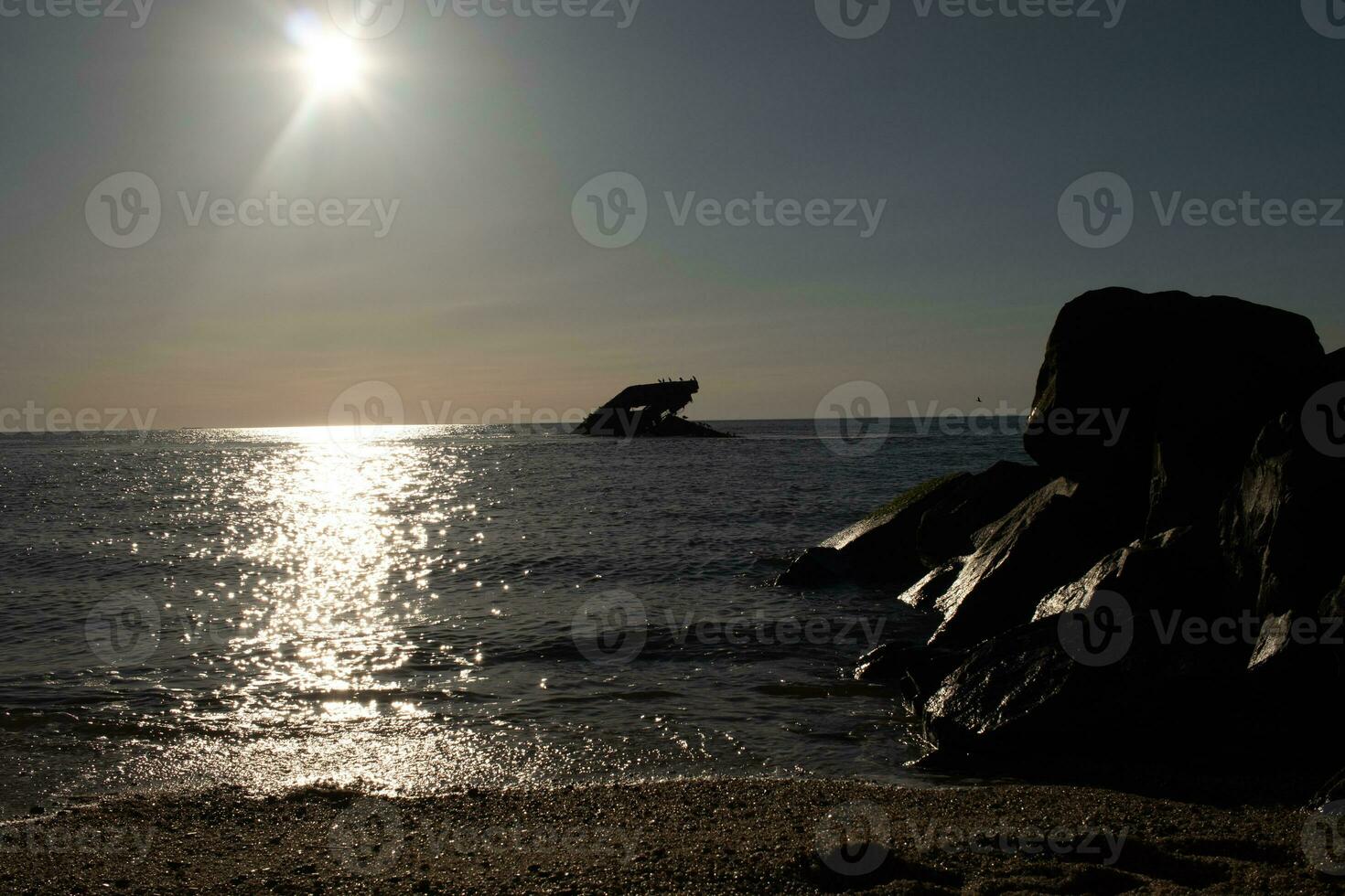Sunset beach in Cape May New Jersey where you can get a great view of the sun going down across the ocean and the bay. The reflection of the sun on the water with the sunken ship looks so beautiful. photo