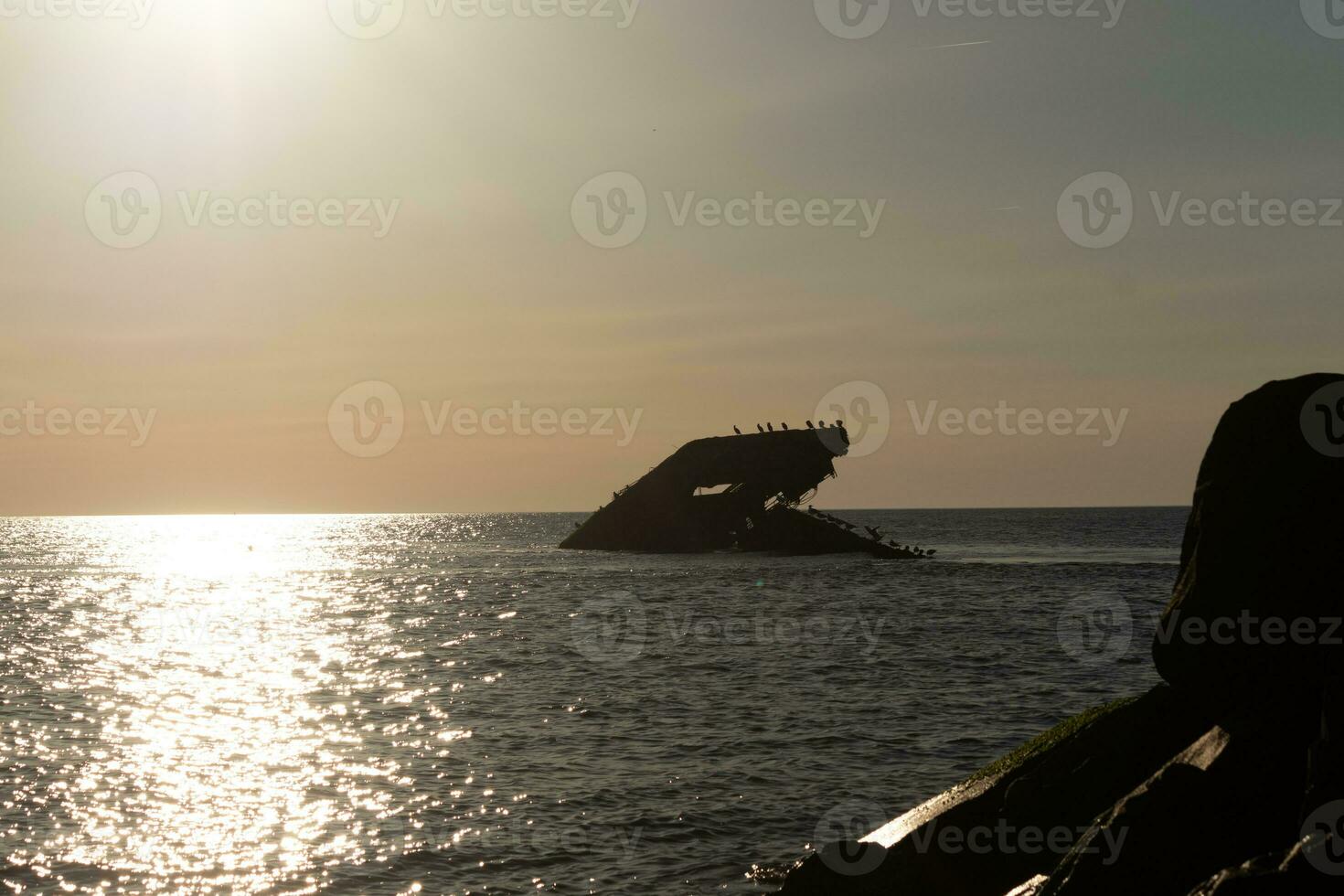 Sunset beach in Cape May New Jersey where you can get a great view of the sun going down across the ocean and the bay. The reflection of the sun on the water with the sunken ship looks so beautiful. photo