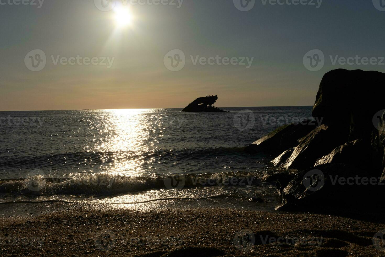 Sunset beach in Cape May New Jersey where you can get a great view of the sun going down across the ocean and the bay. The reflection of the sun on the water with the sunken ship looks so beautiful. photo