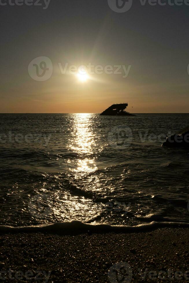 Sunset beach in Cape May New Jersey where you can get a great view of the sun going down across the ocean and the bay. The reflection of the sun on the water with the sunken ship looks so beautiful. photo