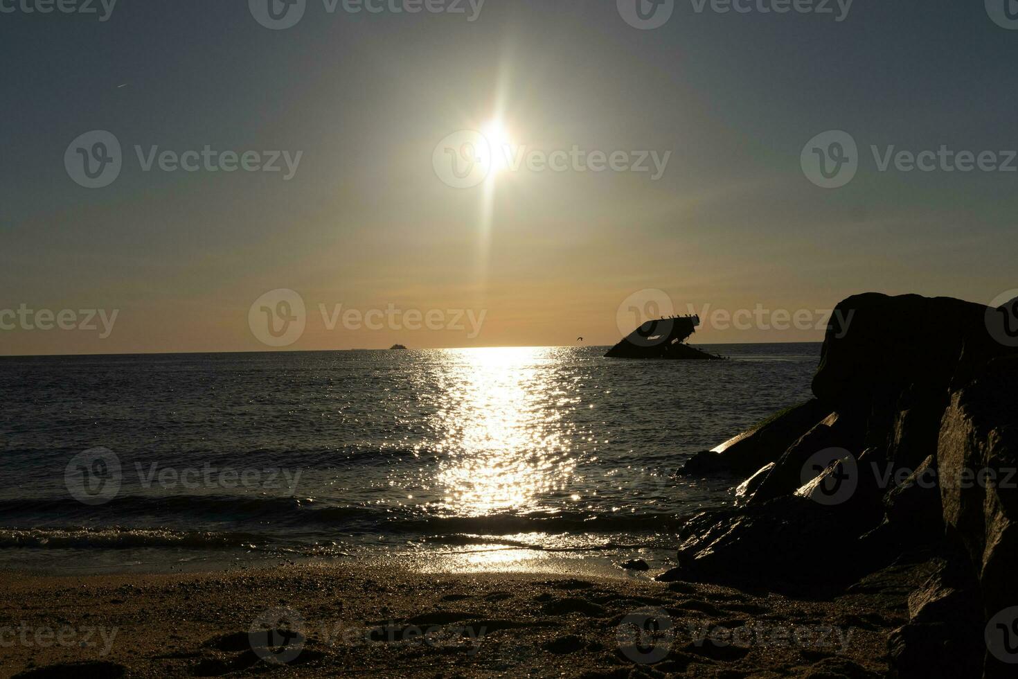 Sunset beach in Cape May New Jersey where you can get a great view of the sun going down across the ocean and the bay. The reflection of the sun on the water with the sunken ship looks so beautiful. photo