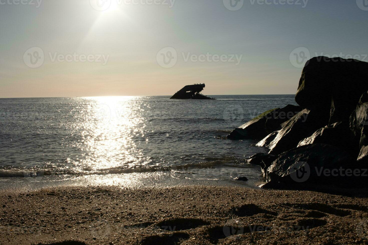 Sunset beach in Cape May New Jersey where you can get a great view of the sun going down across the ocean and the bay. The reflection of the sun on the water with the sunken ship looks so beautiful. photo