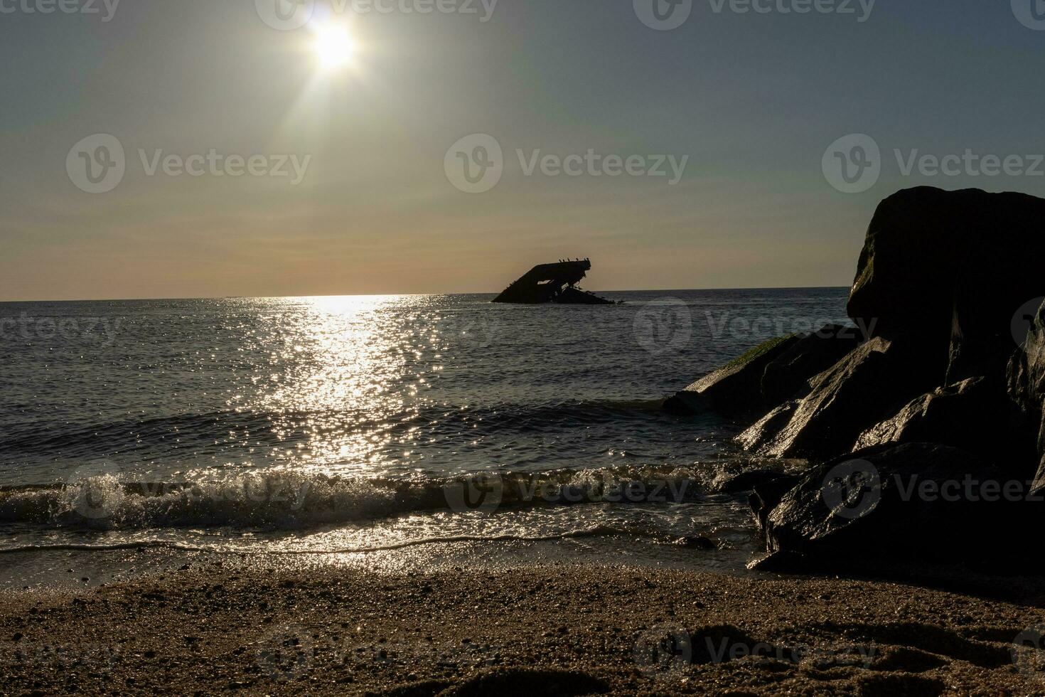 Sunset beach in Cape May New Jersey where you can get a great view of the sun going down across the ocean and the bay. The reflection of the sun on the water with the sunken ship looks so beautiful. photo