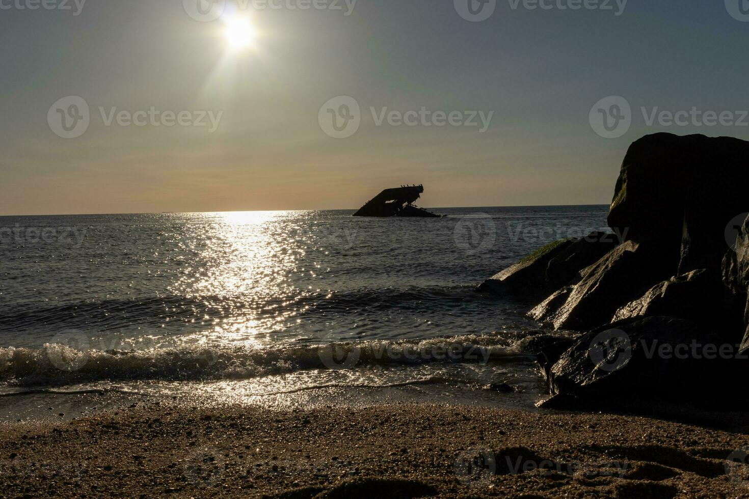 Sunset beach in Cape May New Jersey where you can get a great view of the sun going down across the ocean and the bay. The reflection of the sun on the water with the sunken ship looks so beautiful. photo