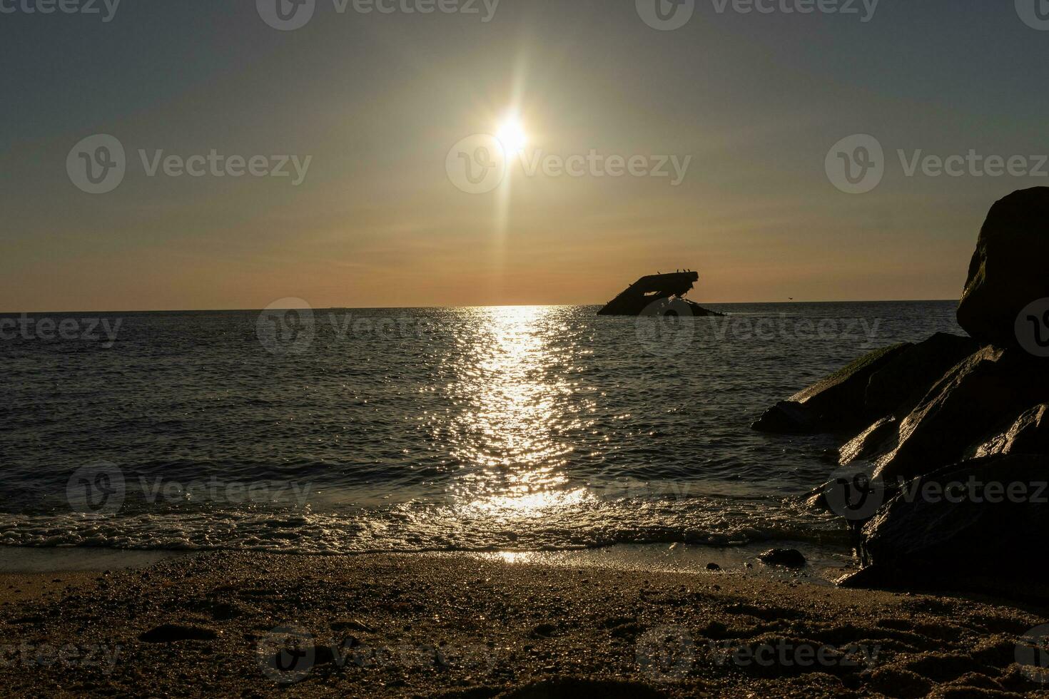 Sunset beach in Cape May New Jersey where you can get a great view of the sun going down across the ocean and the bay. The reflection of the sun on the water with the sunken ship looks so beautiful. photo