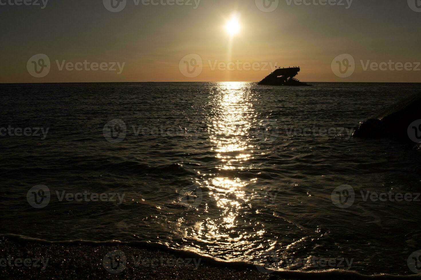 Sunset beach in Cape May New Jersey where you can get a great view of the sun going down across the ocean and the bay. The reflection of the sun on the water with the sunken ship looks so beautiful. photo