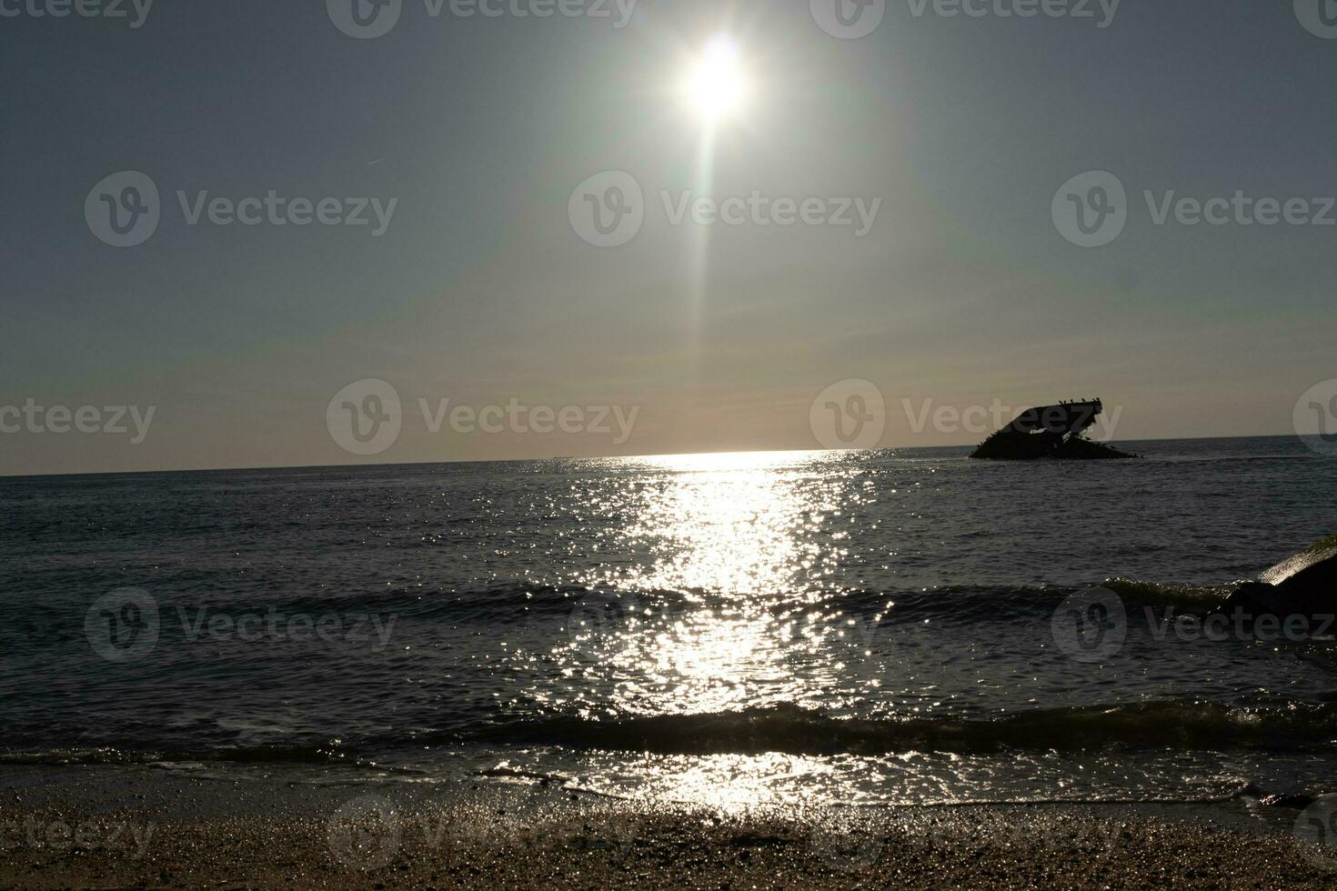 Sunset beach in Cape May New Jersey where you can get a great view of the sun going down across the ocean and the bay. The reflection of the sun on the water with the sunken ship looks so beautiful. photo