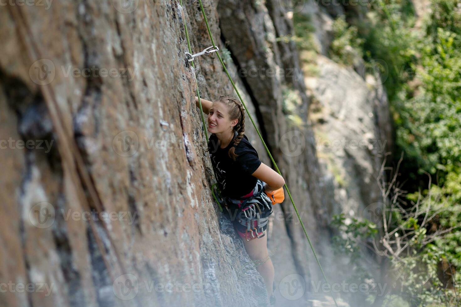 A girl climbs a rock. Woman engaged in extreme sport. photo