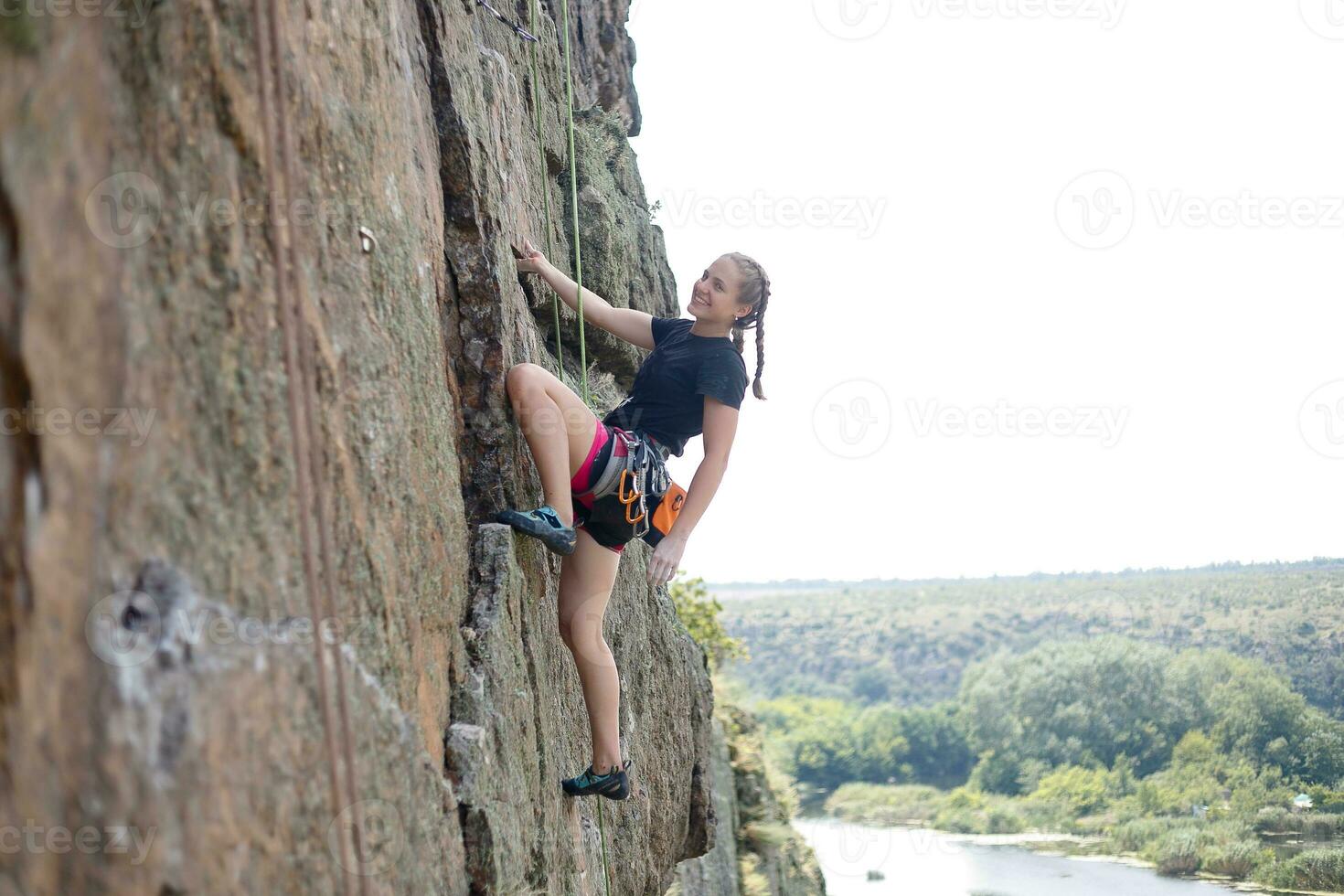 A girl climbs a rock. Woman engaged in extreme sport. photo