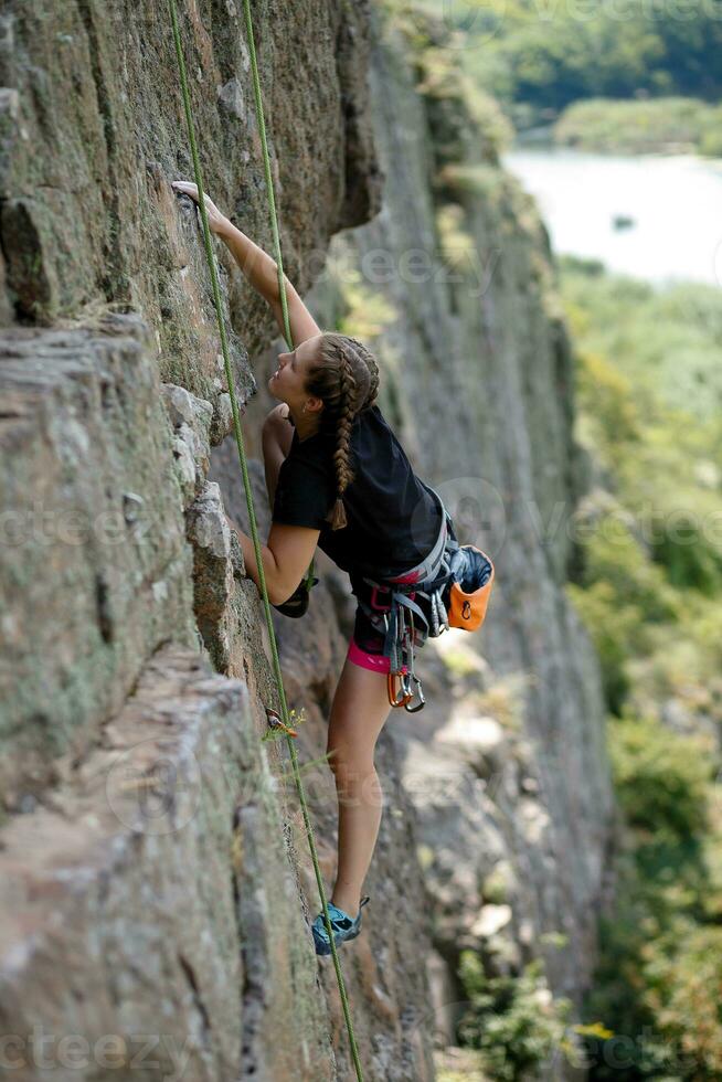 un niña sube un roca. mujer comprometido en extremo deporte. foto