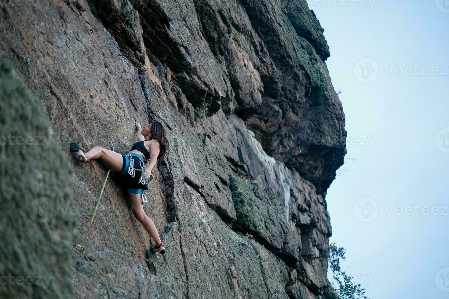 A girl climbs a rock. Woman engaged in extreme sport. photo