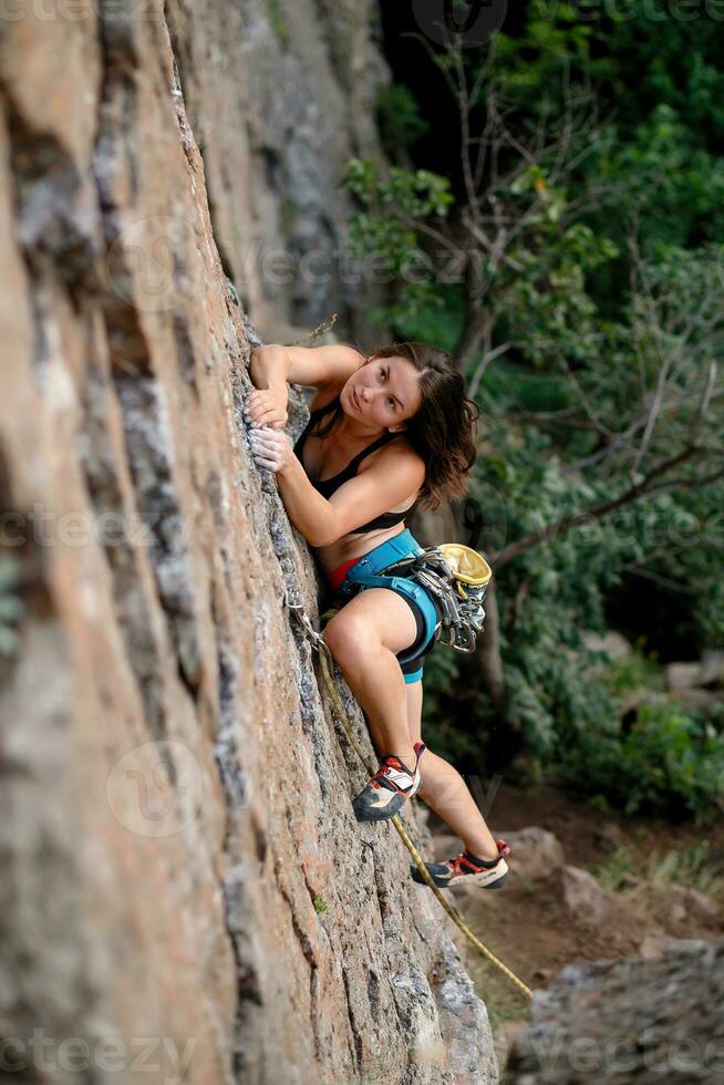 A girl climbs a rock. Woman engaged in extreme sport. photo