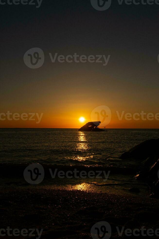 Sunset beach in Cape May New Jersey where you can get a great view of the sun going down across the ocean and the bay. The reflection of the sun on the water with the sunken ship looks so beautiful. photo