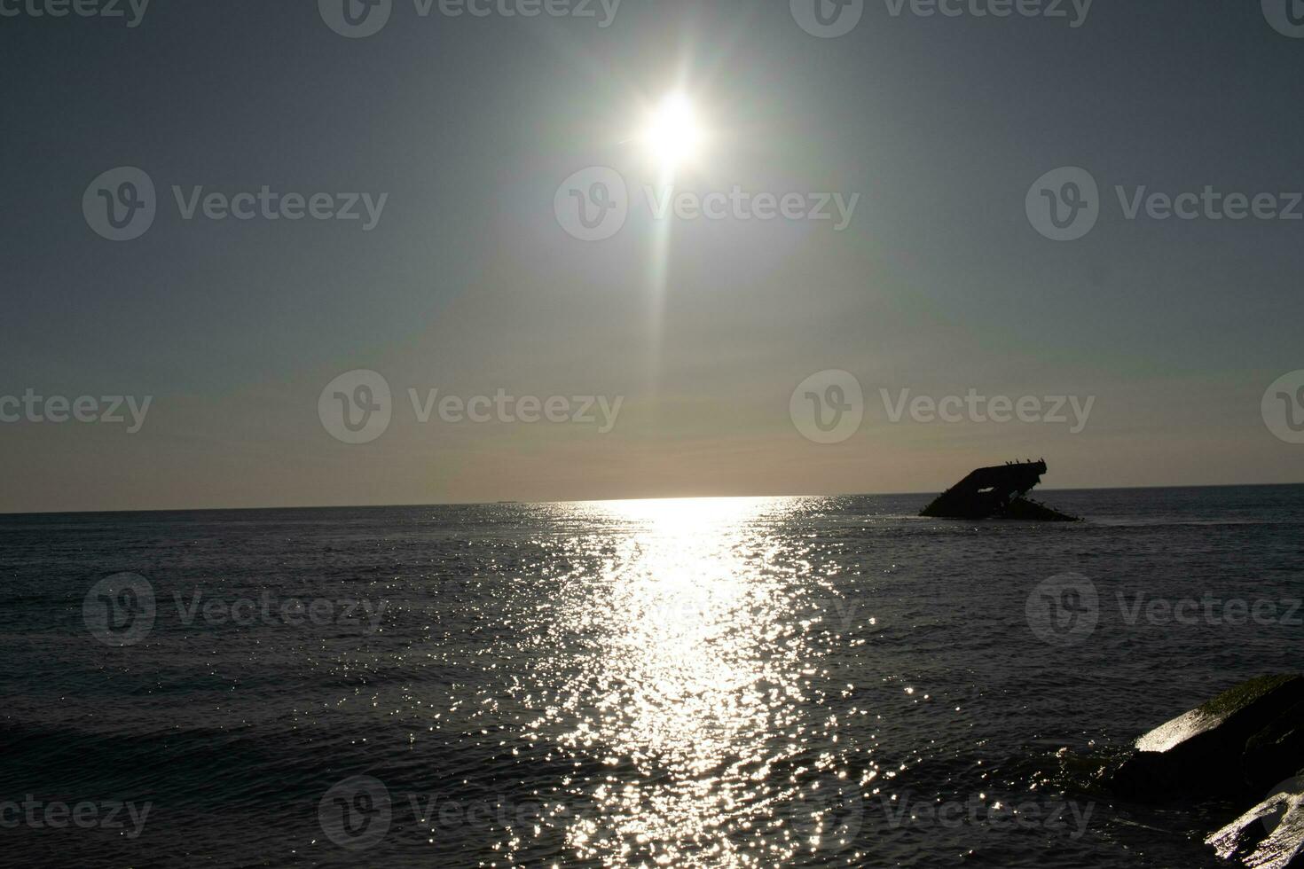 Sunset beach in Cape May New Jersey where you can get a great view of the sun going down across the ocean and the bay. The reflection of the sun on the water with the sunken ship looks so beautiful. photo