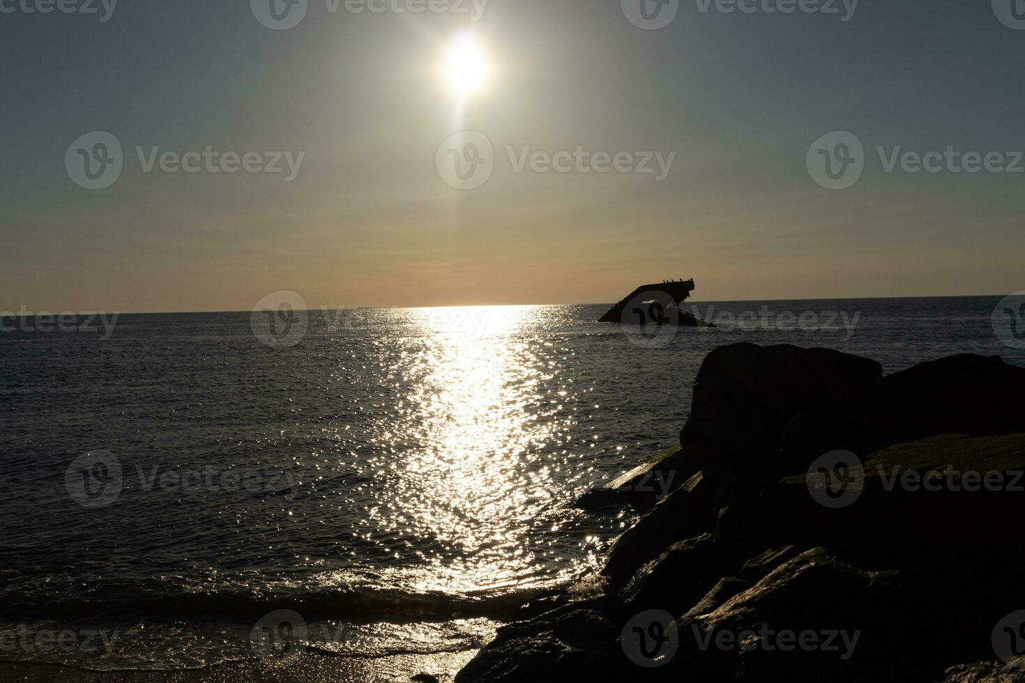 Sunset beach in Cape May New Jersey where you can get a great view of the sun going down across the ocean and the bay. The reflection of the sun on the water with the sunken ship looks so beautiful. photo