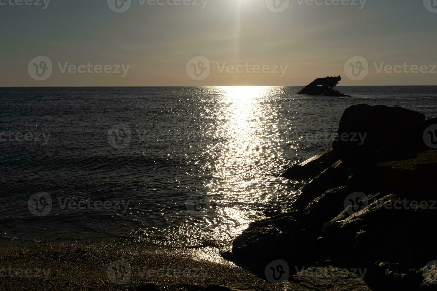 Sunset beach in Cape May New Jersey where you can get a great view of the sun going down across the ocean and the bay. The reflection of the sun on the water with the sunken ship looks so beautiful. photo
