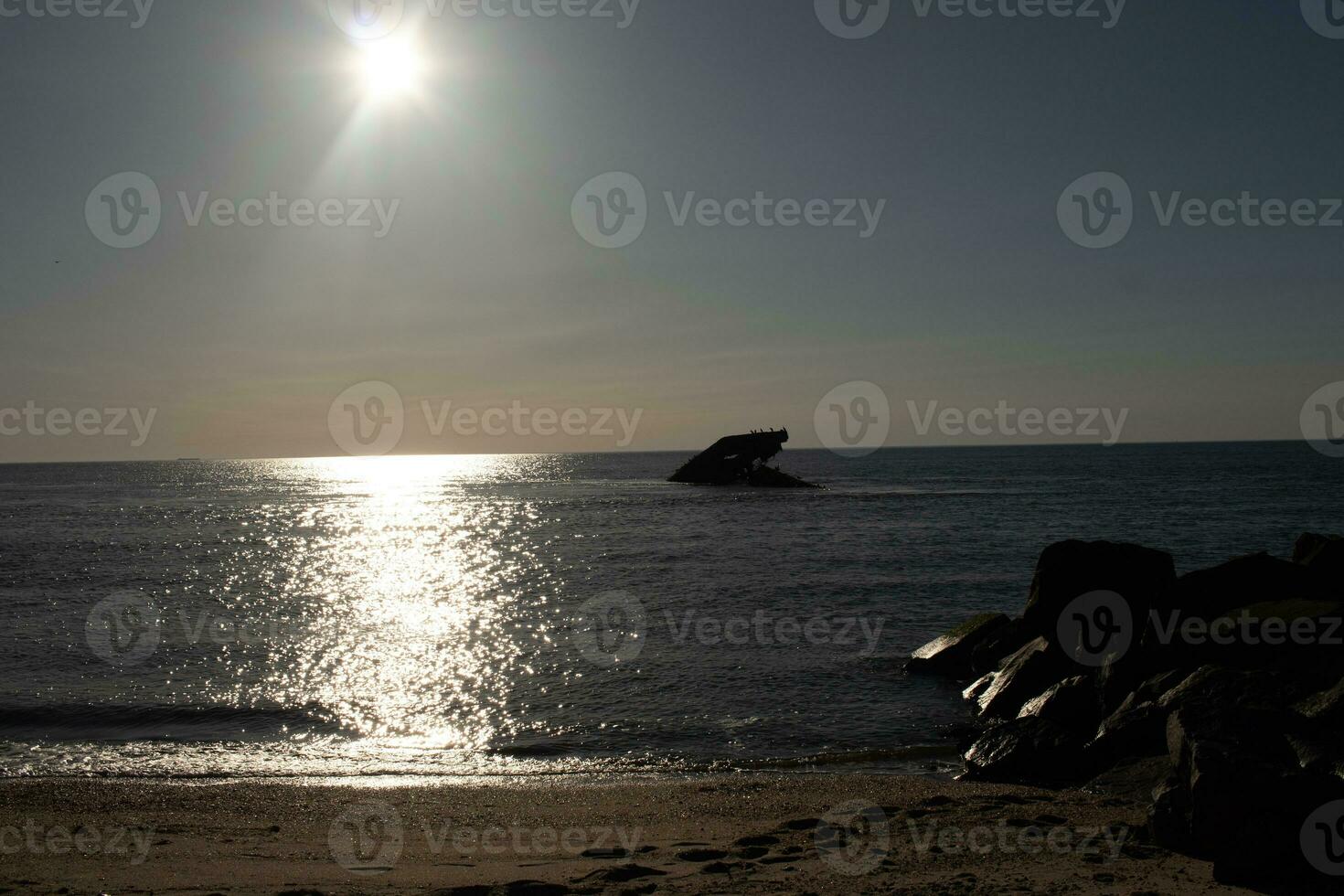 Sunset beach in Cape May New Jersey where you can get a great view of the sun going down across the ocean and the bay. The reflection of the sun on the water with the sunken ship looks so beautiful. photo